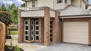 A modern two-story house with a garage, brick exterior, and a covered entryway. - Signature Townhouse in Doncaster (Doncaster East)