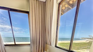 Una habitación de hotel con una cama, dos ventanas y vista a la playa.