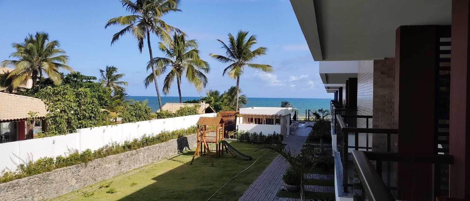 Une vue d’un hôtel avec une piscine, des palmiers et une plage en arrière-plan.