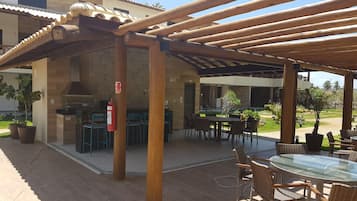 An outdoor patio with wooden pergola, tables, chairs, and potted plants.