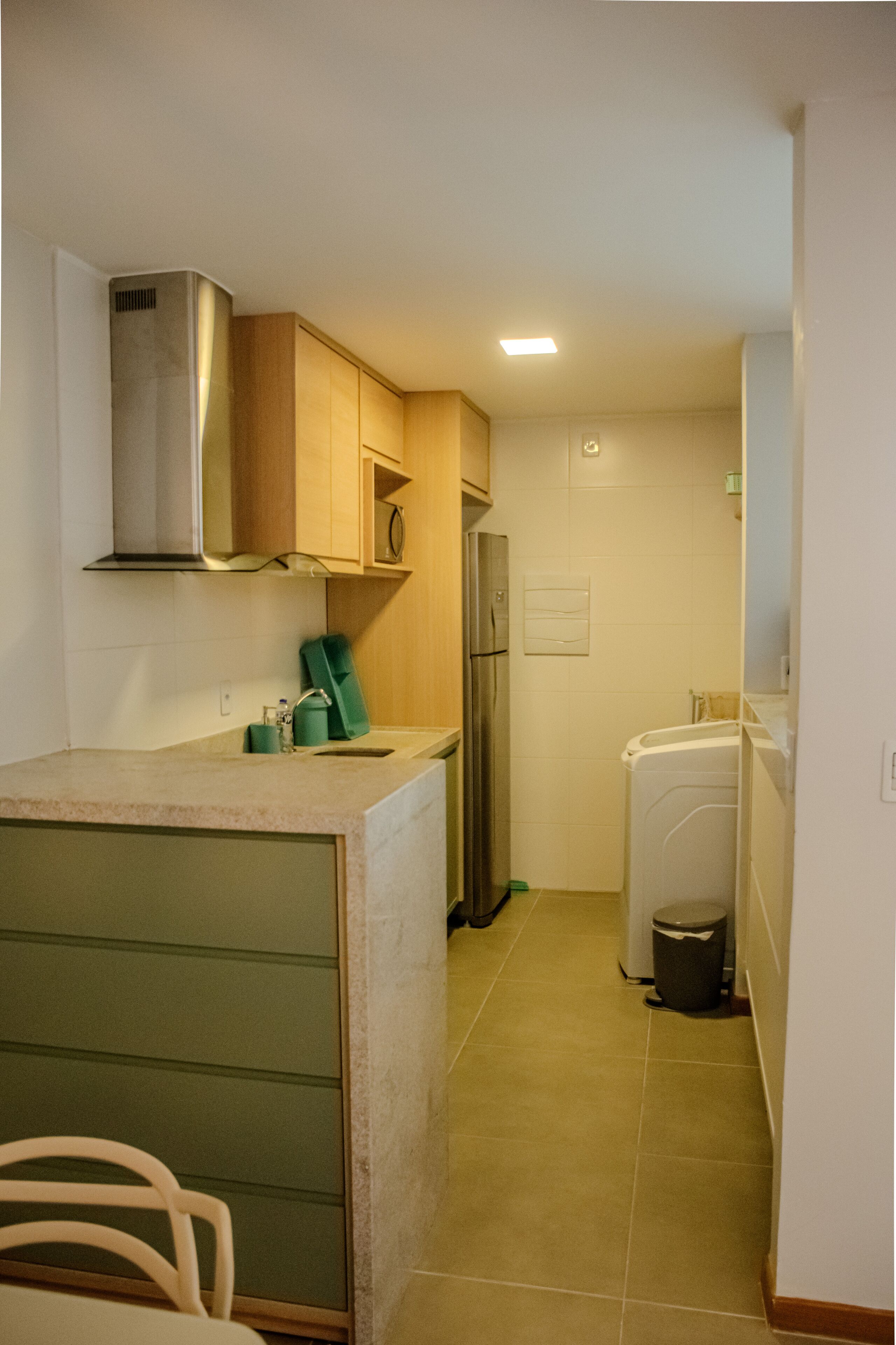 A compact kitchen with a built-in stove, a refrigerator, and a washing machine.