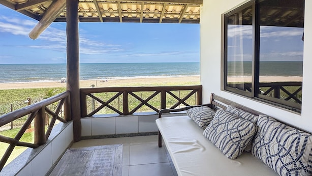 Un espacio de estar al aire libre techado con vista a la playa.