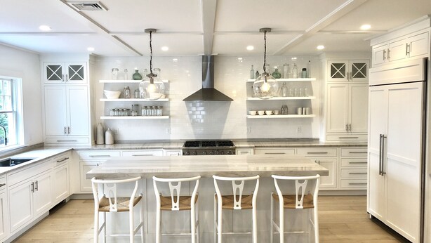 A modern kitchen with white cabinetry, a central island with bar stools, and pendant lighting. - Stunning In-Town Home With Stone Hot Tub - Plunge Pool (Nantucket)
