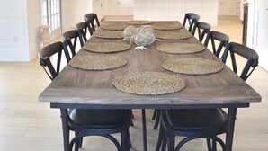 A spacious dining area with a large wooden table, black chairs, and a hanging light fixture. - Stunning In-Town Home With Stone Hot Tub - Plunge Pool (Nantucket)