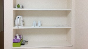 Un estante blanco con una tetera, dos tazas y una caja de pañuelos.