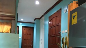 A hallway with teal walls, wooden doors, and a refrigerator. - TSL Unit H Well furnished Apartment (Cebu)