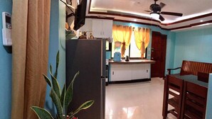 A compact living space with a kitchenette, a dining area with a wooden table and chairs, and a ceiling fan. - TSL Unit H Well furnished Apartment (Cebu)