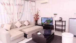 Una sala de estar moderna con un sofá, una mesa de centro, un televisor y una mesita auxiliar con una tetera.