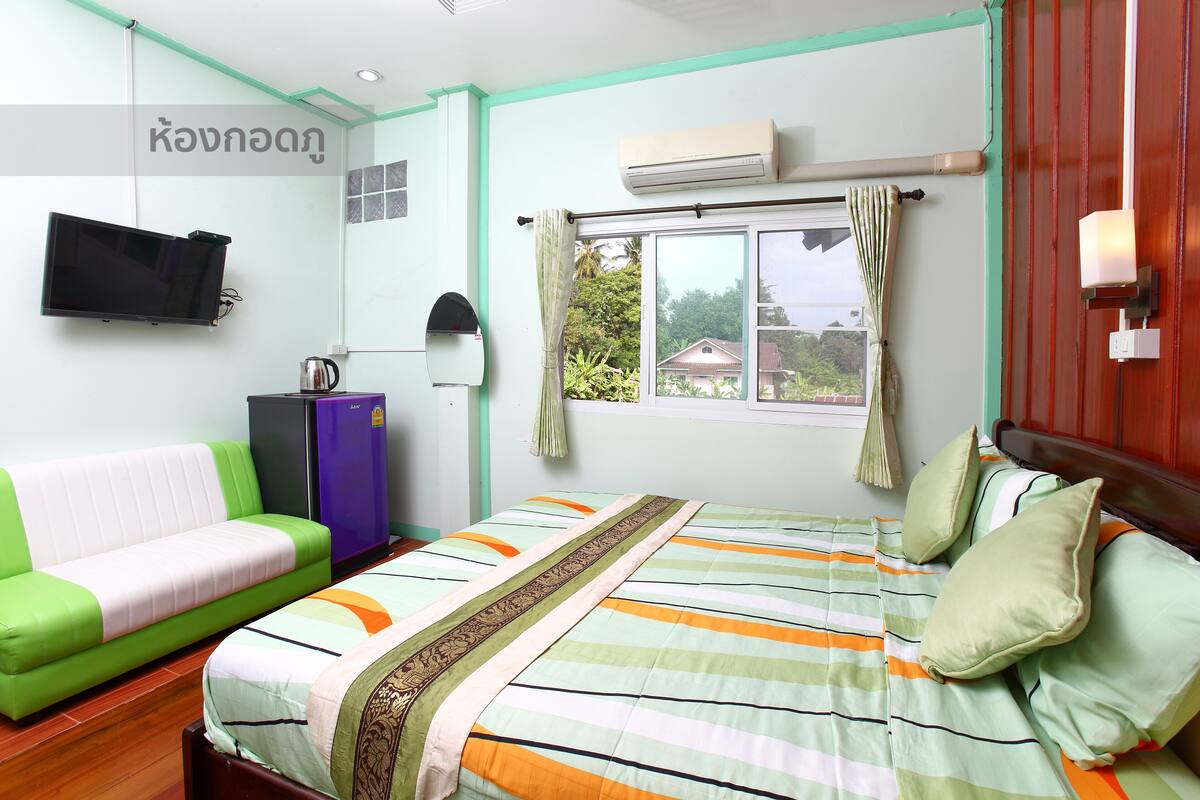 Een kamer met een bed, een bank, een televisie en airconditioning.