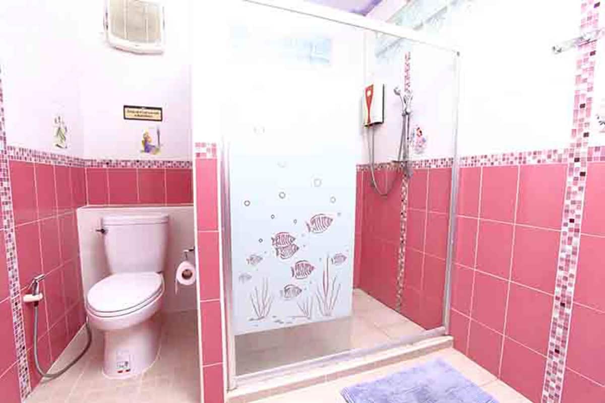 Een badkamer met toilet, douche en decoratieve vistegels.