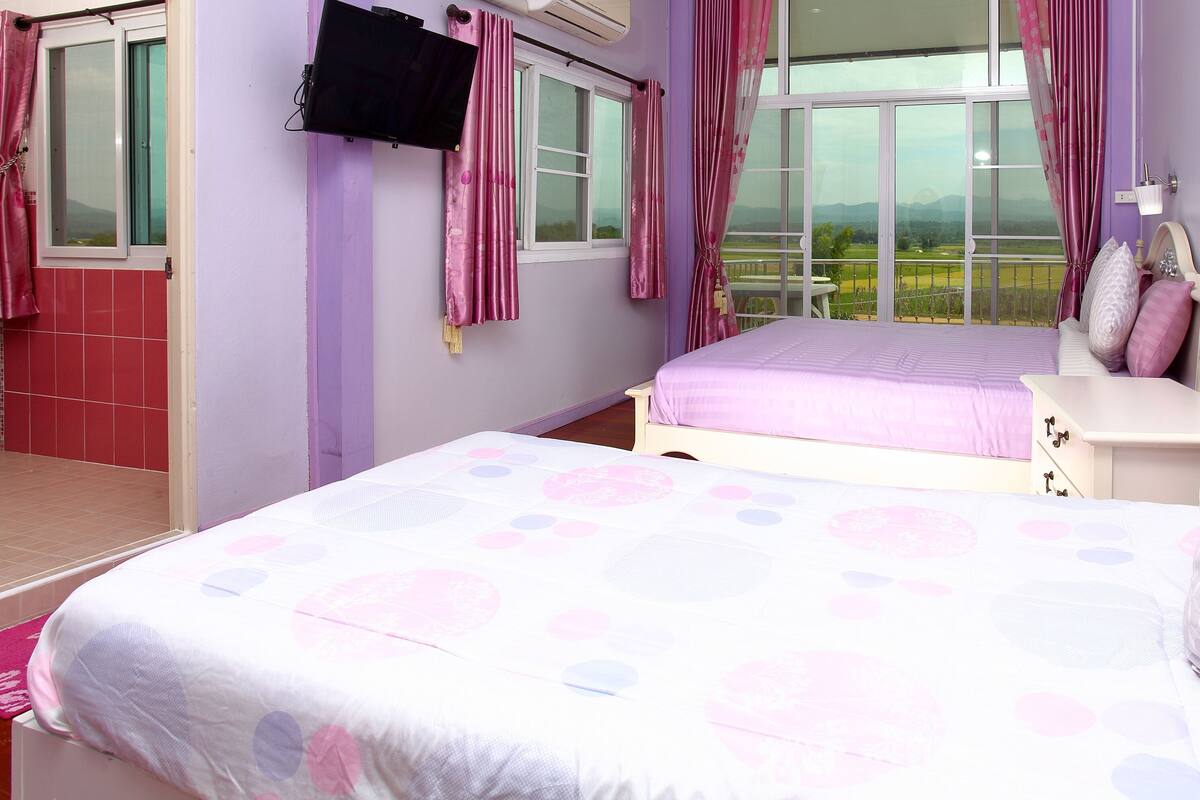 Een slaapkamer met twee bedden, een aan de muur bevestigde televisie en een balkon met uitzicht.