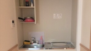A compact kitchenette with a sink, a small refrigerator, and a trash bin. - uenohouse annex (Tokyo)