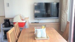 A compact kitchen with a wooden table, two chairs, a microwave, and a small cabinet. - uenohouse annex (Tokyo)
