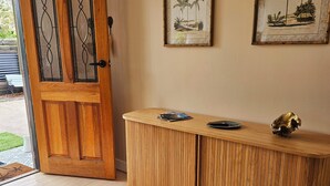A wooden door with glass panels, a wooden console table with a decorative item, and two framed botanical prints on the wall.