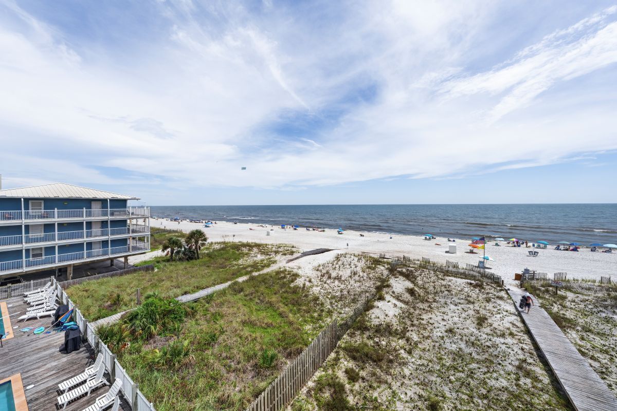 Uitzicht op een strand met een gebouw, een houten terras en een zandstrand.