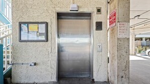 An elevator with a sign indicating parking information and a warning about booted vehicles. - Sundial G3- The Beach is Where You Need to Be! (Gulf Shores)