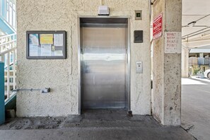 An elevator with a sign indicating parking information and a warning about booted vehicles. - Sundial G3- The Beach is Where You Need to Be! (Gulf Shores)