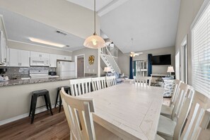A spacious kitchen with a large island, white cabinetry, and a dining area with a long table and chairs.