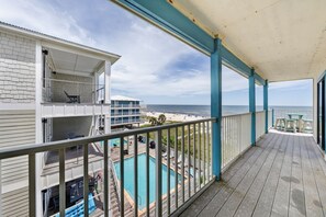 Ein mehrstöckiges Gebäude mit einem Balkon, der einen Pool und einen Strand überblickt.