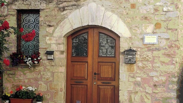 Un edificio de piedra con puerta y contraventanas de madera, con la inscripción "Casa Maria".
