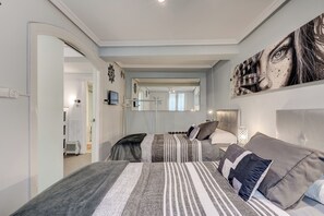 A bedroom with two beds, a large mirror, and a view into another room.