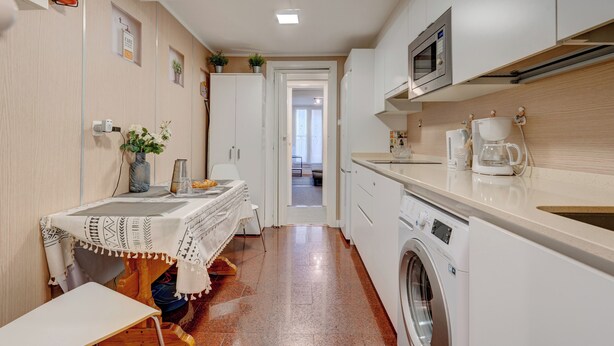 Een kleine keuken met een wasmachine, een magnetron en een koffiezetapparaat.