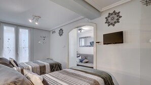 Een slaapkamer met twee bedden, een televisie en een spiegel.