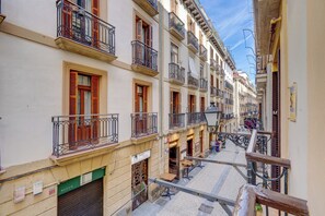 Una calle estrecha con edificios que tienen balcones y contraventanas.