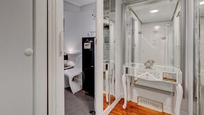Een kamer met een witte deur, een glazen scheidingswand, een wit bureau met een spiegel en een bord waarop 'WELCOME' staat.
