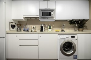 Una cocina moderna equipada con microondas, cafetera y lavadora.