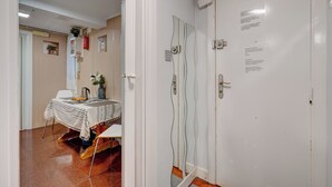 Een kamer met een witte deur, een tafel met een wit tafelkleed, een potplant en een spiegel met een golvend frame.
