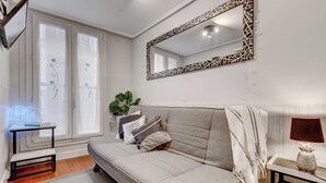 Een moderne woonkamer met een bank, een spiegel, een plant en een lamp.
