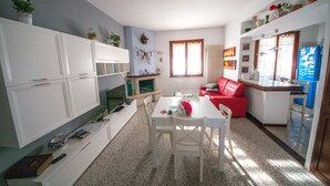 Espaço compacto com área de refeições, um sofá vermelho e cozinha com janela.