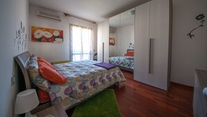 Quarto com duas camas, um tapete verde e um armário com espelho.