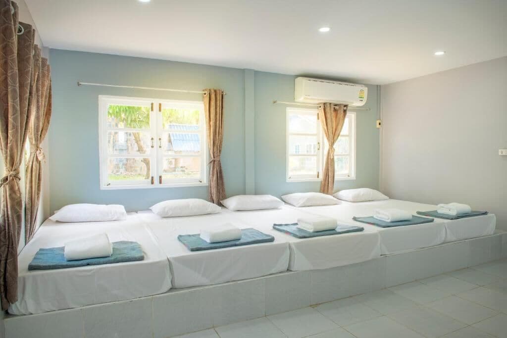 Habitación de hotel con dos camas, ropa blanca y un ventanal con cortinas.
