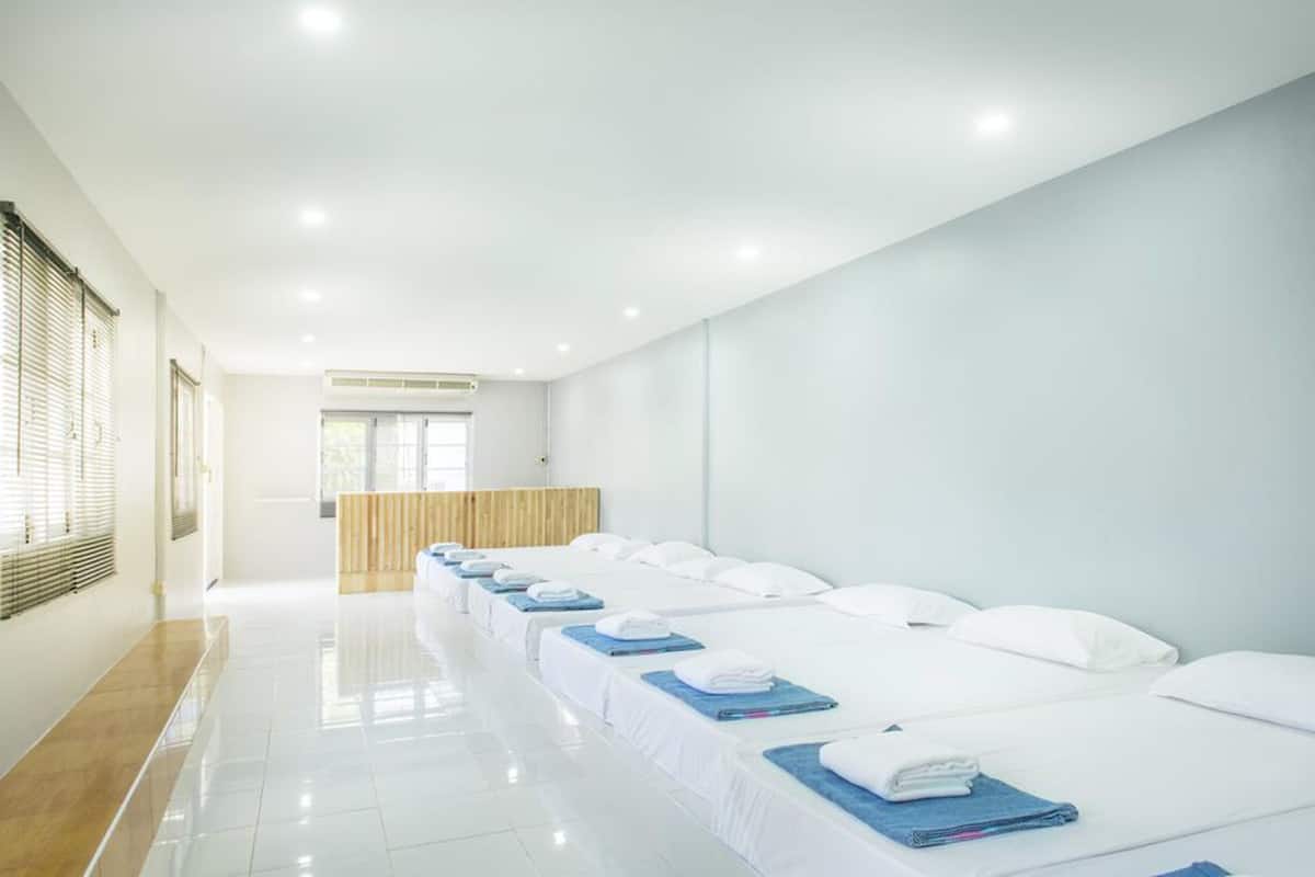 A hotel room with a row of beds, a wooden reception desk, and a bright, well-lit interior.