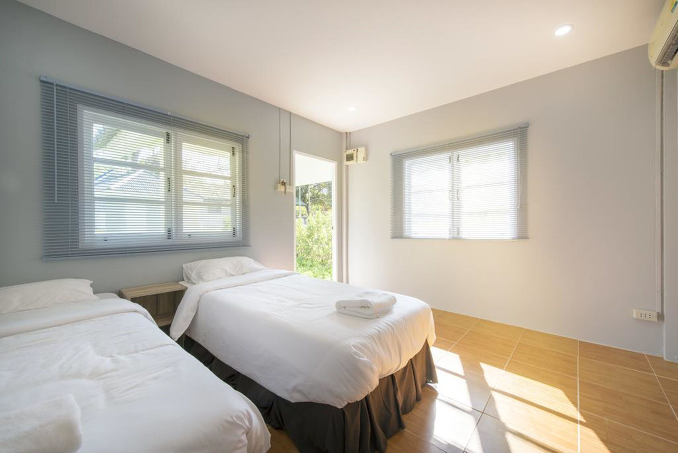 Une chambre d’hôtel avec deux lits, de grandes fenêtres et une vue sur la verdure environnante.