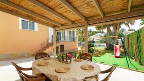 Eine Terrasse im Freien mit einem Esstisch und Holzsesseln.