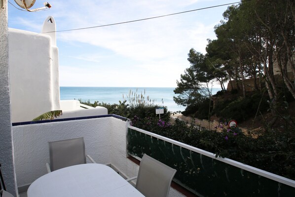 Ein Balkon mit Tisch und Stühlen mit Blick auf einen Strand und das Meer.