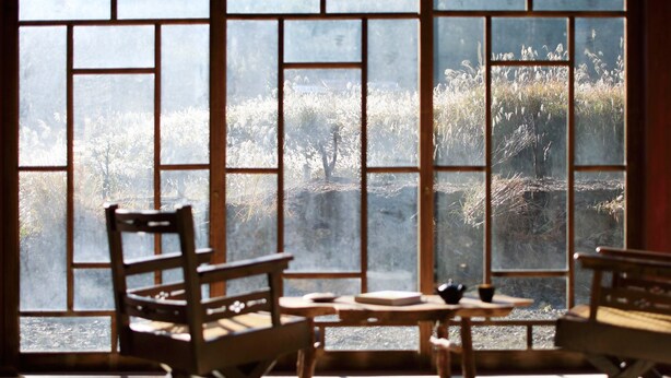 A room with large windows, wooden furniture, and a view of a natural landscape. - The Lodge MIWA (Kyoto)