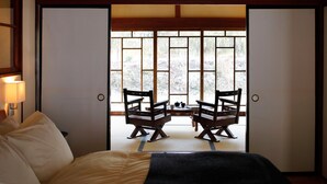 A traditional Japanese room with tatami flooring, a low table with a tea set, and sliding doors leading to a garden. - The Lodge MIWA (Kyoto)