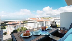 A balcony with a table set for breakfast, overlooking a coastal cityscape. - Serene Horizon - BY SCH (Nazaré)
