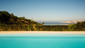 A swimming pool with a view of the sea and a landscaped area. - Serene Horizon - BY SCH (Nazaré)