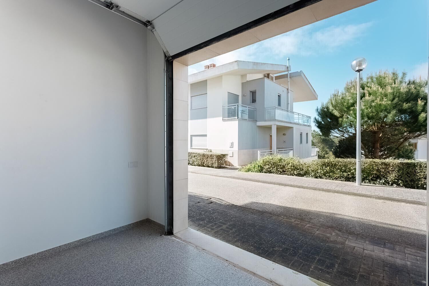 Un appartement moderne doté d’une grande fenêtre, d’un balcon et offrant une vue sur une rue résidentielle.