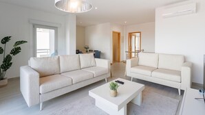 A modern living room with two sofas, a coffee table, and a large pendant light. - Serene Horizon - BY SCH (Nazaré)
