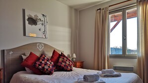 Un lit bien fait, avec un oreiller à motifs, une table de chevet avec une lampe et une fenêtre avec des rideaux.