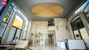 Um hall amplo com teto alto, grandes janelas e um balcão de recepção.
