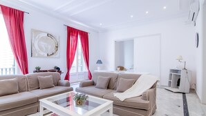 A modern living room with a beige sectional sofa, a glass coffee table, and red curtains. - Large two bedroom apartment (Barcelona)