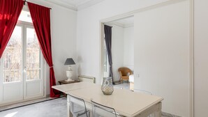 A room with a white table, red curtains, a lamp, and a chair. - Large two bedroom apartment (Barcelona)