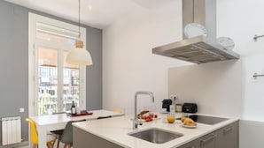 Eine moderne Küche mit einer zentralen Kochinsel, einer eingebauten Spüle und einem Fenster mit Blick auf eine Stadtlandschaft.